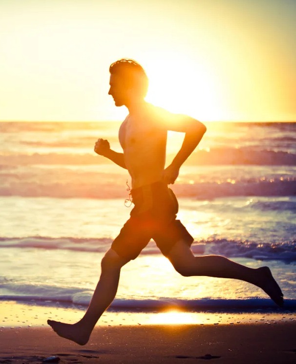 Barefoot runner on the beach at sunrise